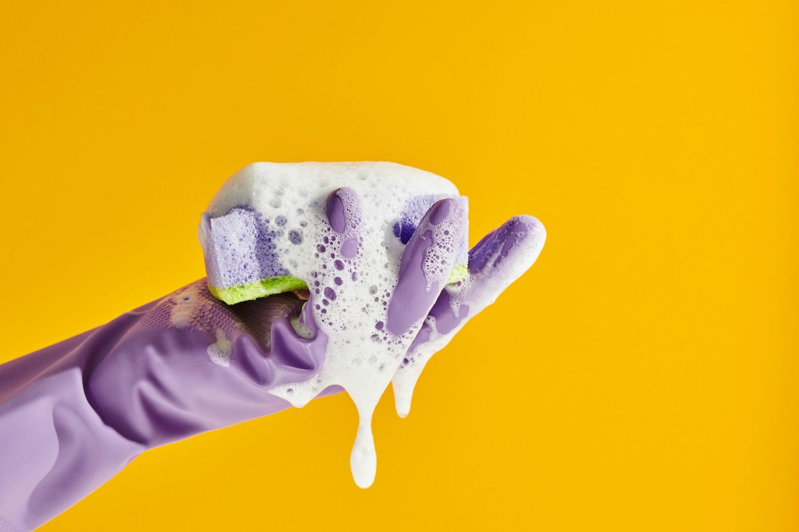 A gloved hand holding a soapy sponge, illustrating the effectiveness of natural cleaning products in maintaining a safe, chemical-free home environment. Embrace eco-friendly solutions for a healthier home wellness sanctuary.
