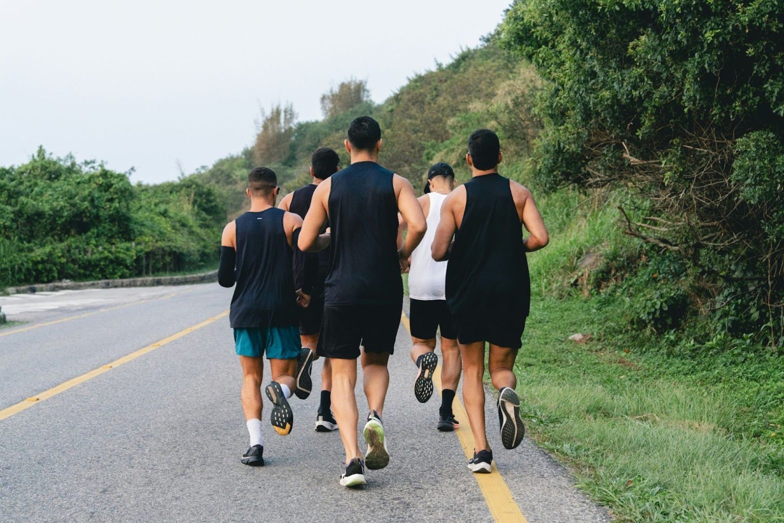 Group of men running outdoors on a road, representing active lifestyles, fitness routines, and sustainable habits that support weight loss for men.